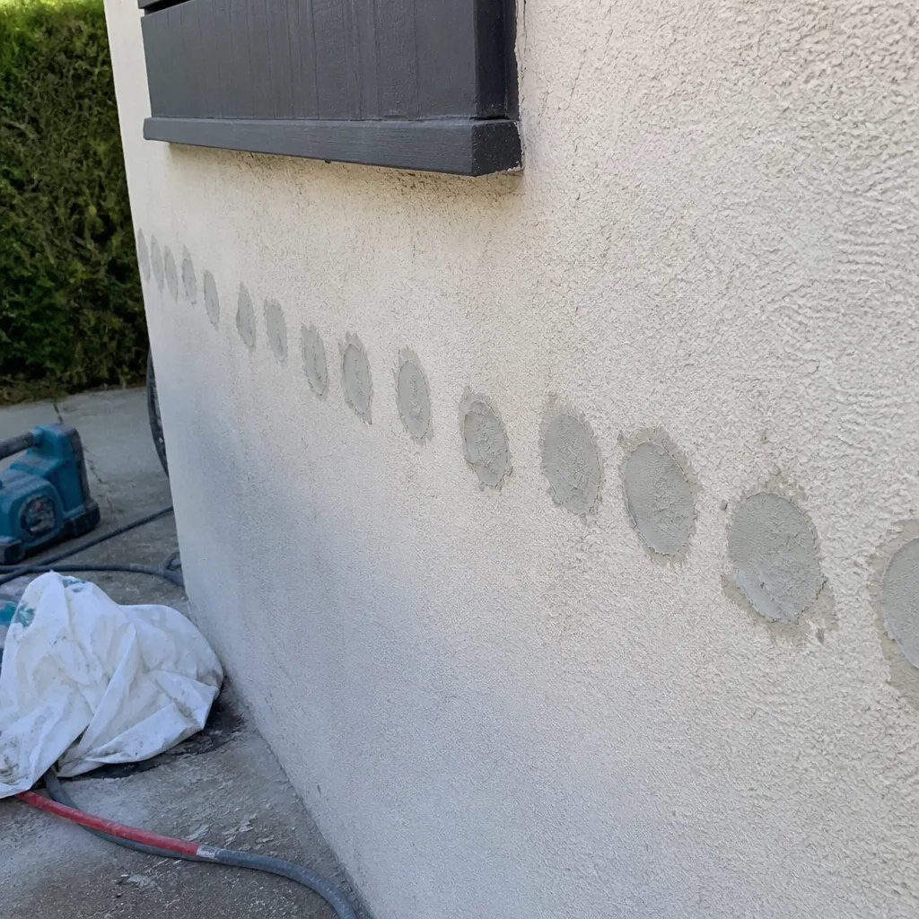 professional wall insulation installation showing plugged access holes on stucco wall nationwide